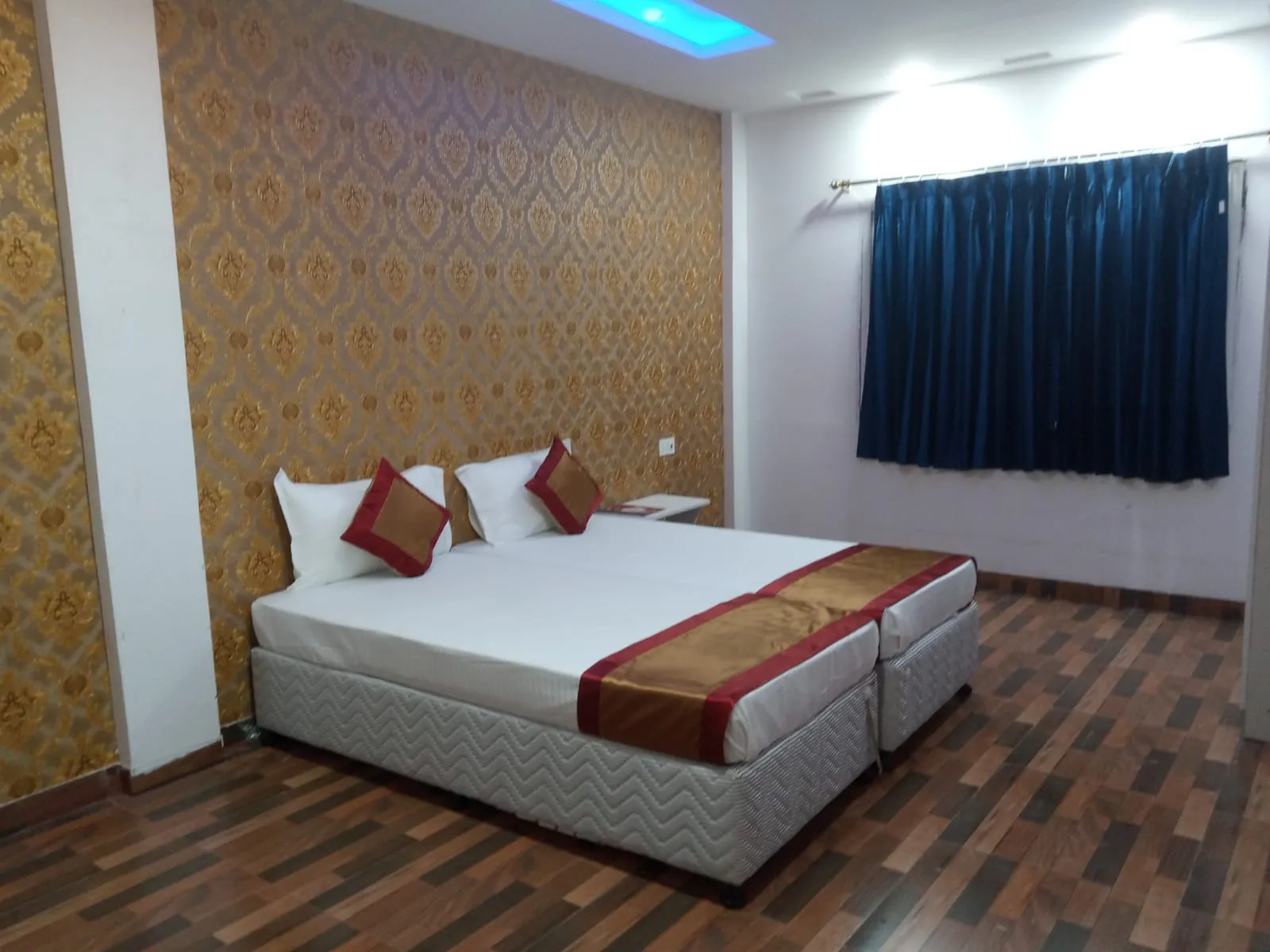 Hotel room with a double bed and gold damask wallpaper
