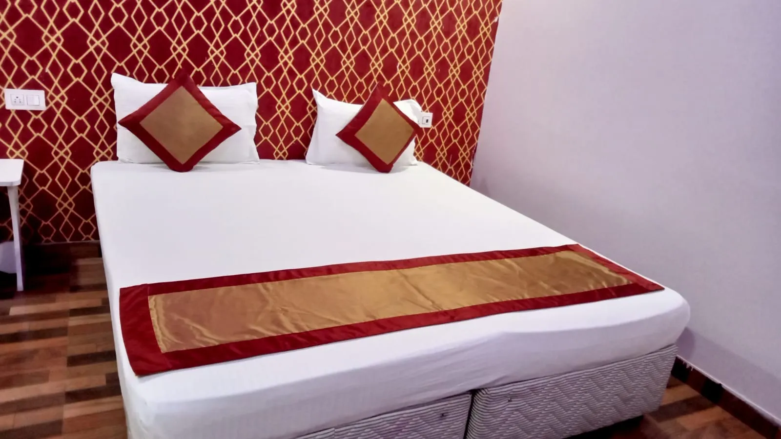 Hotel room with a double bed against a red and gold patterned wall