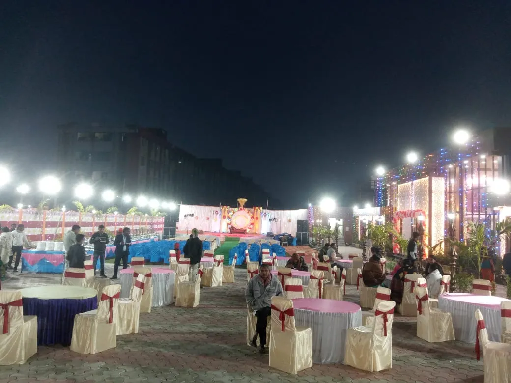 The party lawn set up at night with round tables, chairs and a stage for an event