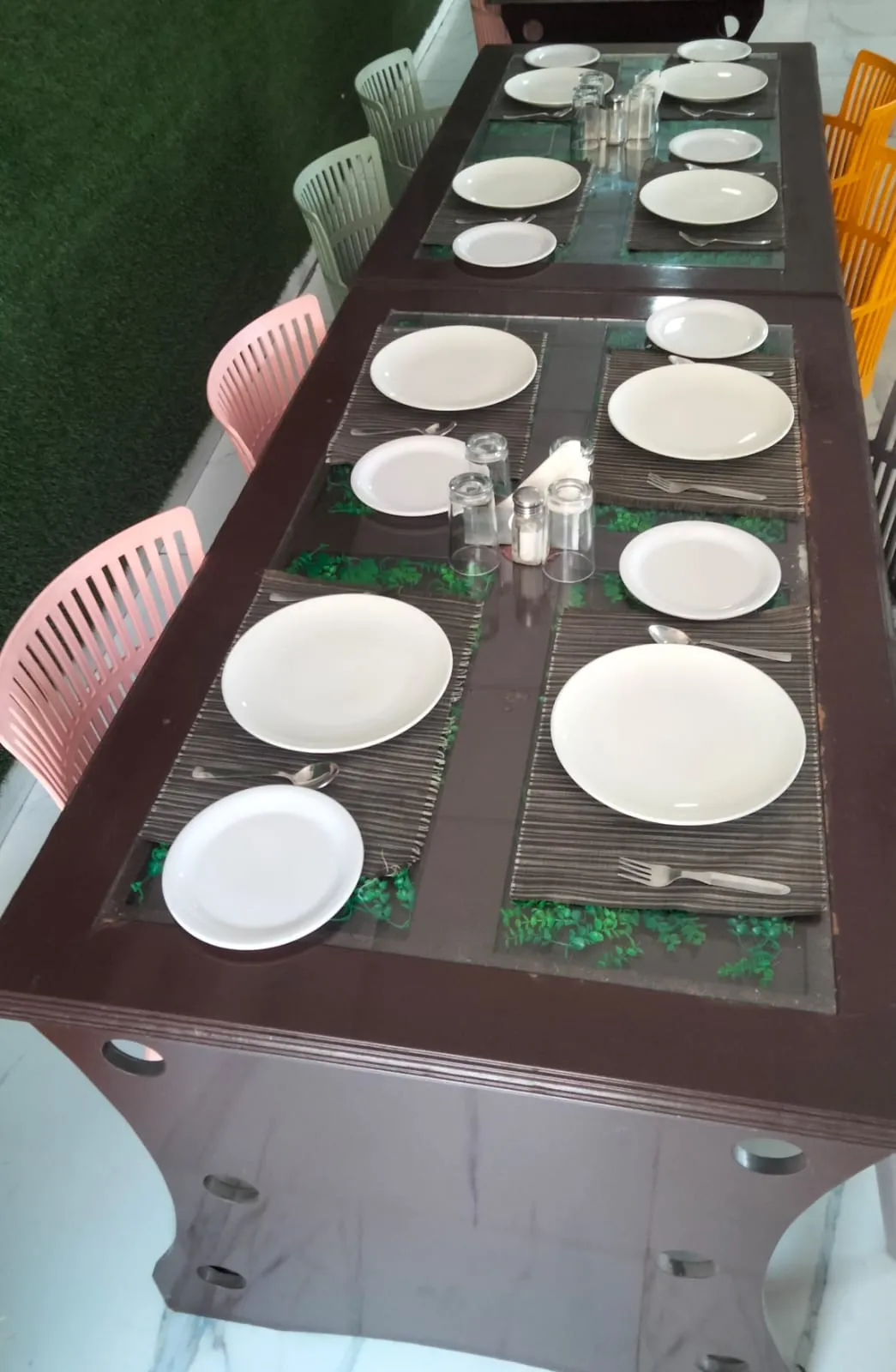 Close overhead view of a table laid with plates, cutlery and glassware for a group