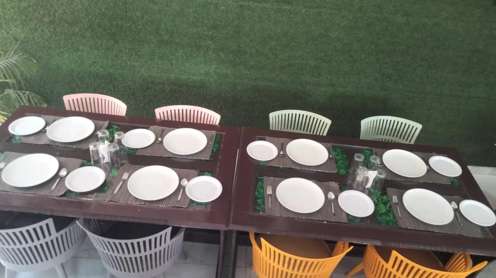 Two long tables laid for a group on the restaurant's patio, backed by an artificial turf wall
