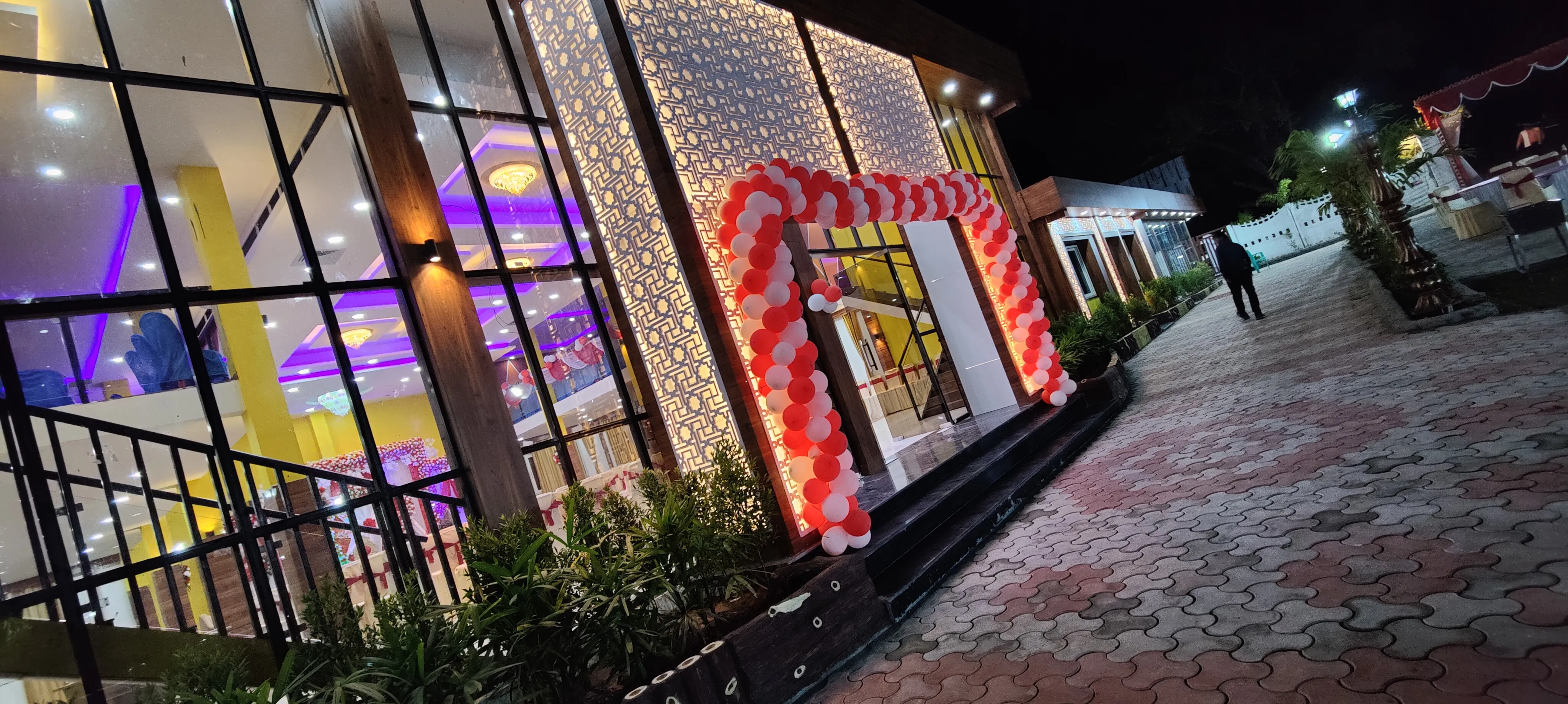 The decorated venue entrance at night, seen from outside, with the lit hall visible through the glass
